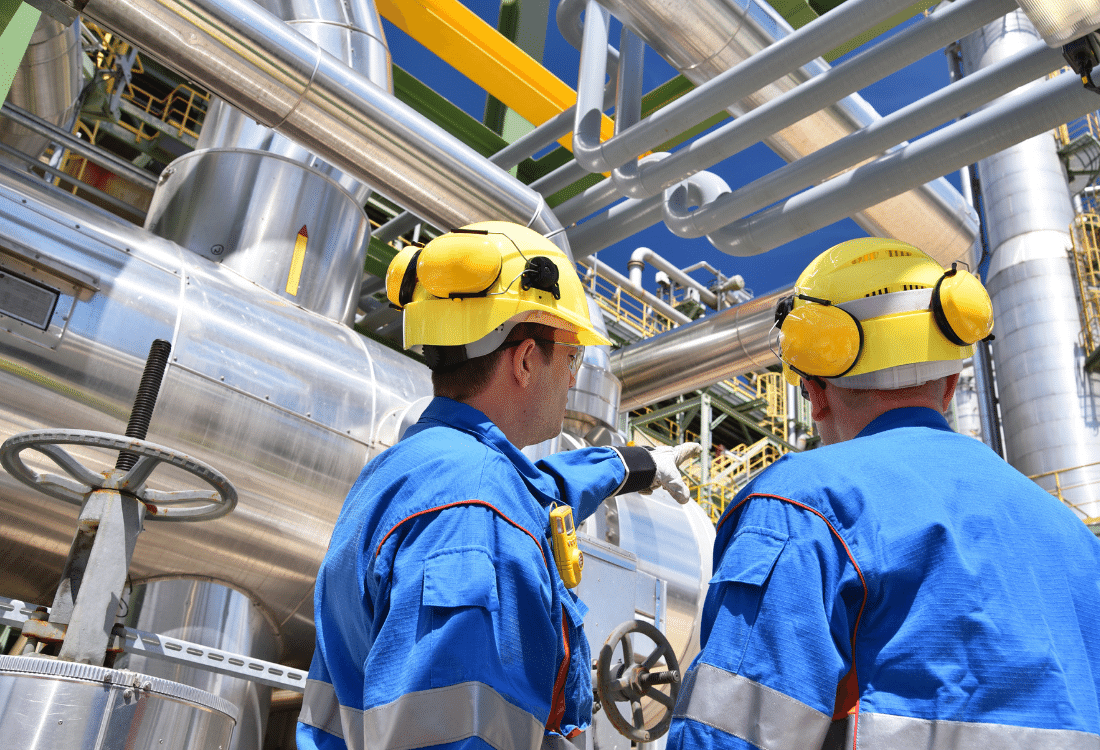 Two industrial workers in an oil refinery plant that adheres to all compliance standards to ensure their health and safety is looked after 